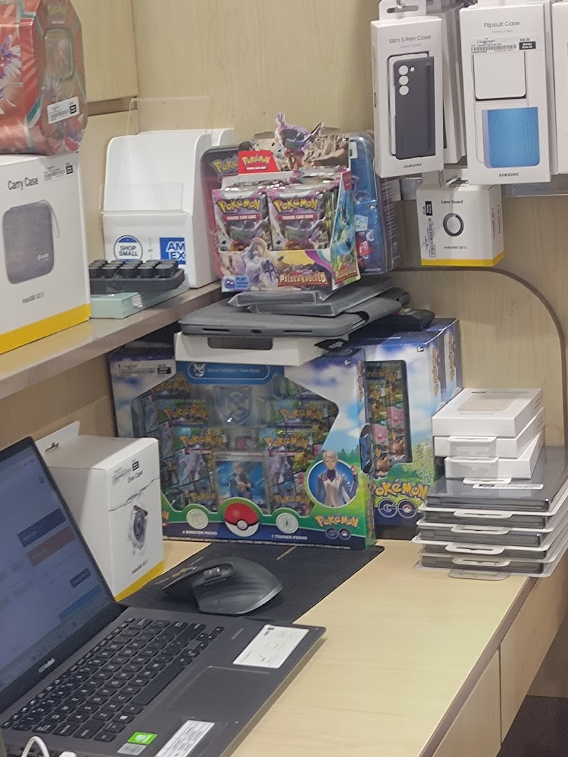 Interior shot of a retail display with Pokémon products, phone accessories, and a laptop.