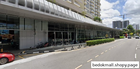 Exterior view of a modern building with glass shop fronts and parked bicycles.