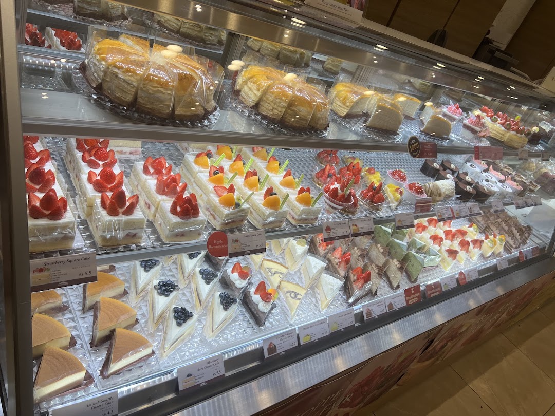 A refrigerated display case filled with various cakes and pastries.