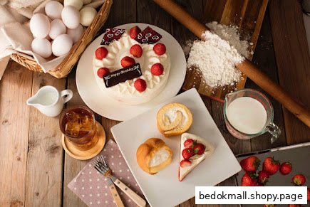 Assortment of cakes, pastries, and baking ingredients on a wooden table.