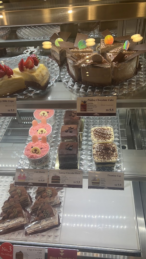 Cakes and desserts displayed in a glass case with price tags.