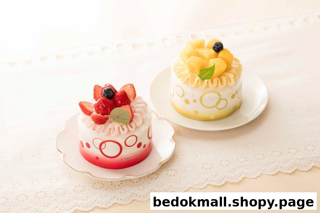 Two decorated cakes, one strawberry and one mango, on white plates.