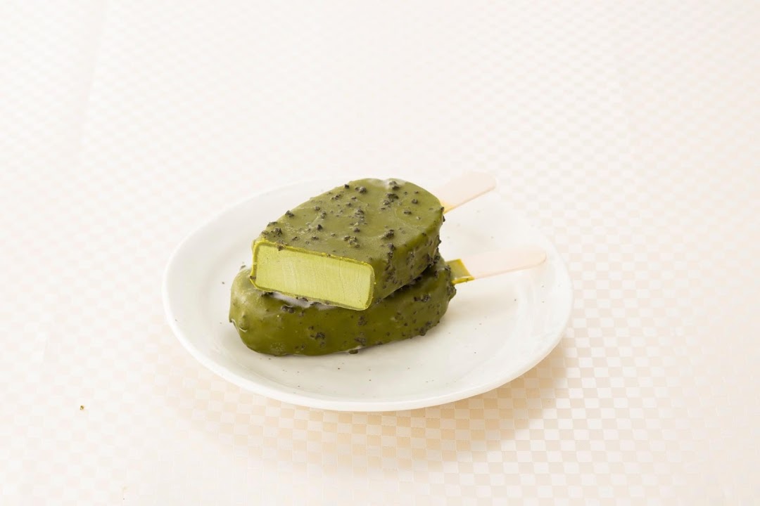 Two green ice cream bars on a white plate, one cut open.