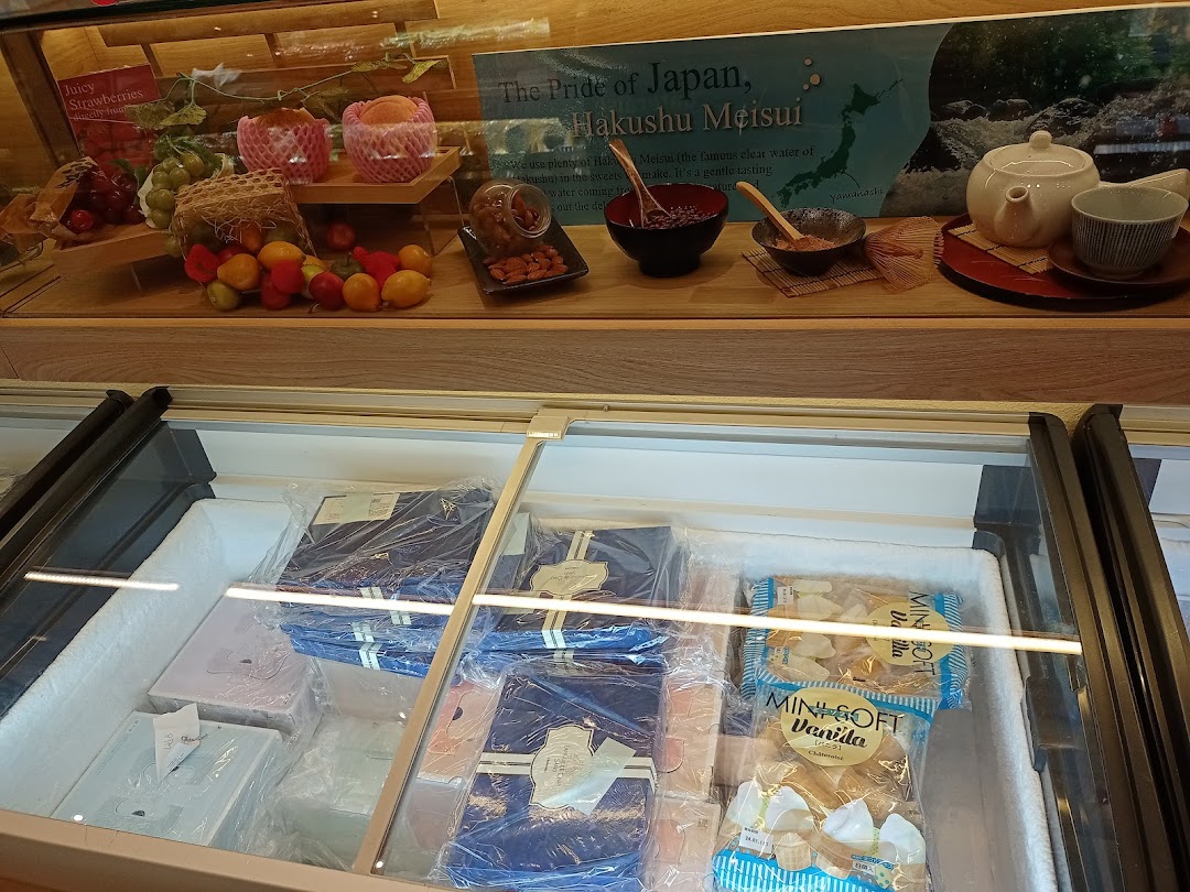 Interior view of a shop with a display case and freezer full of products.