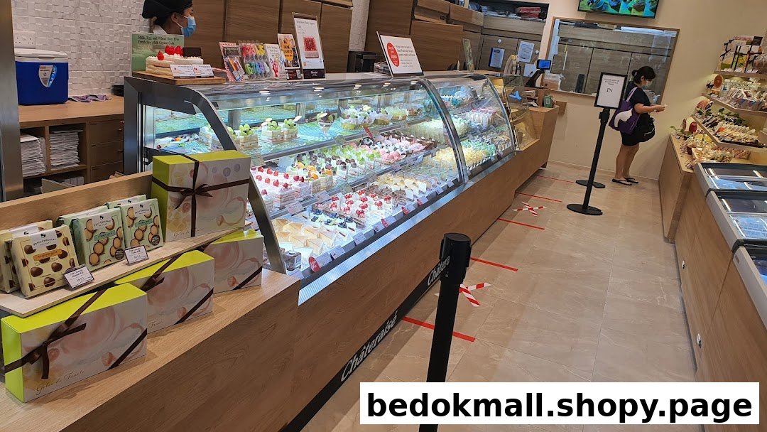 Interior view of a bakery with a large display case of cakes and pastries.