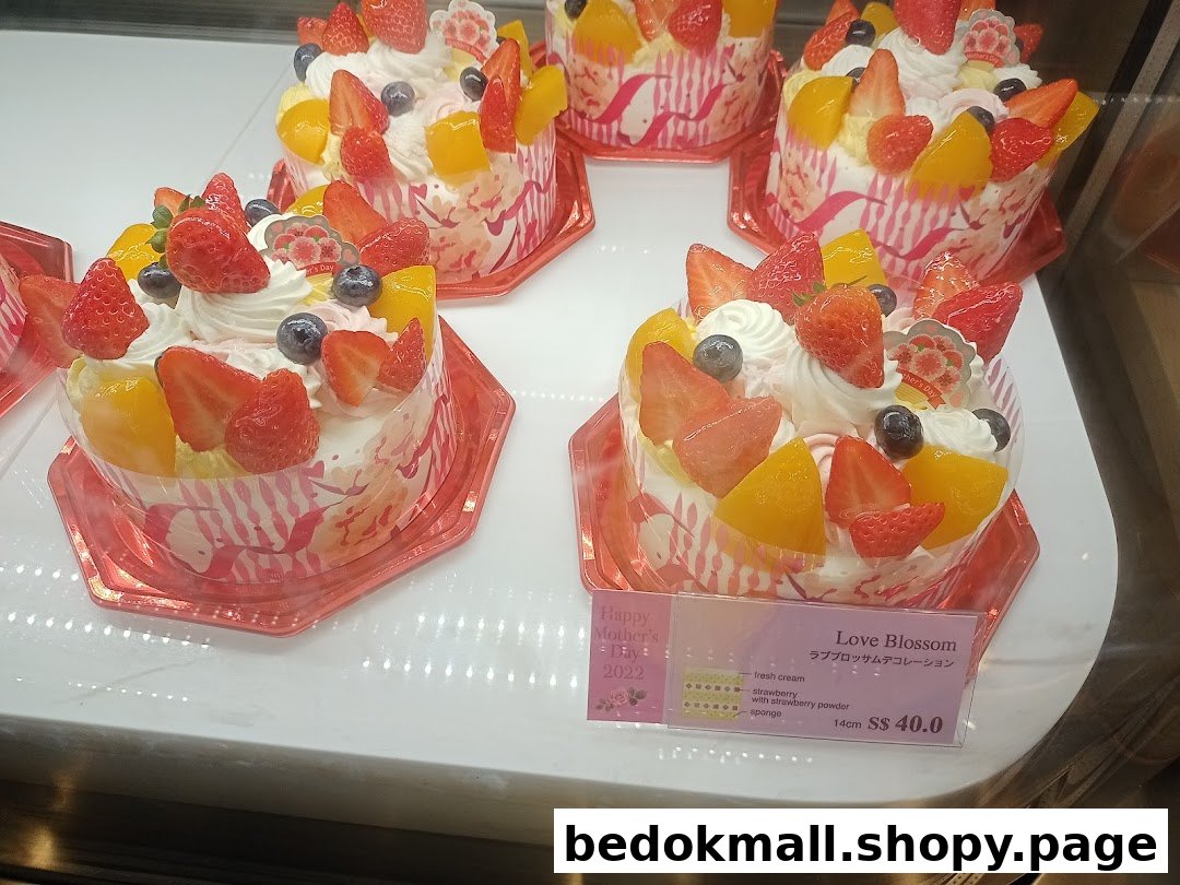 Multiple fruit-topped cakes displayed in a refrigerated case with a price tag.