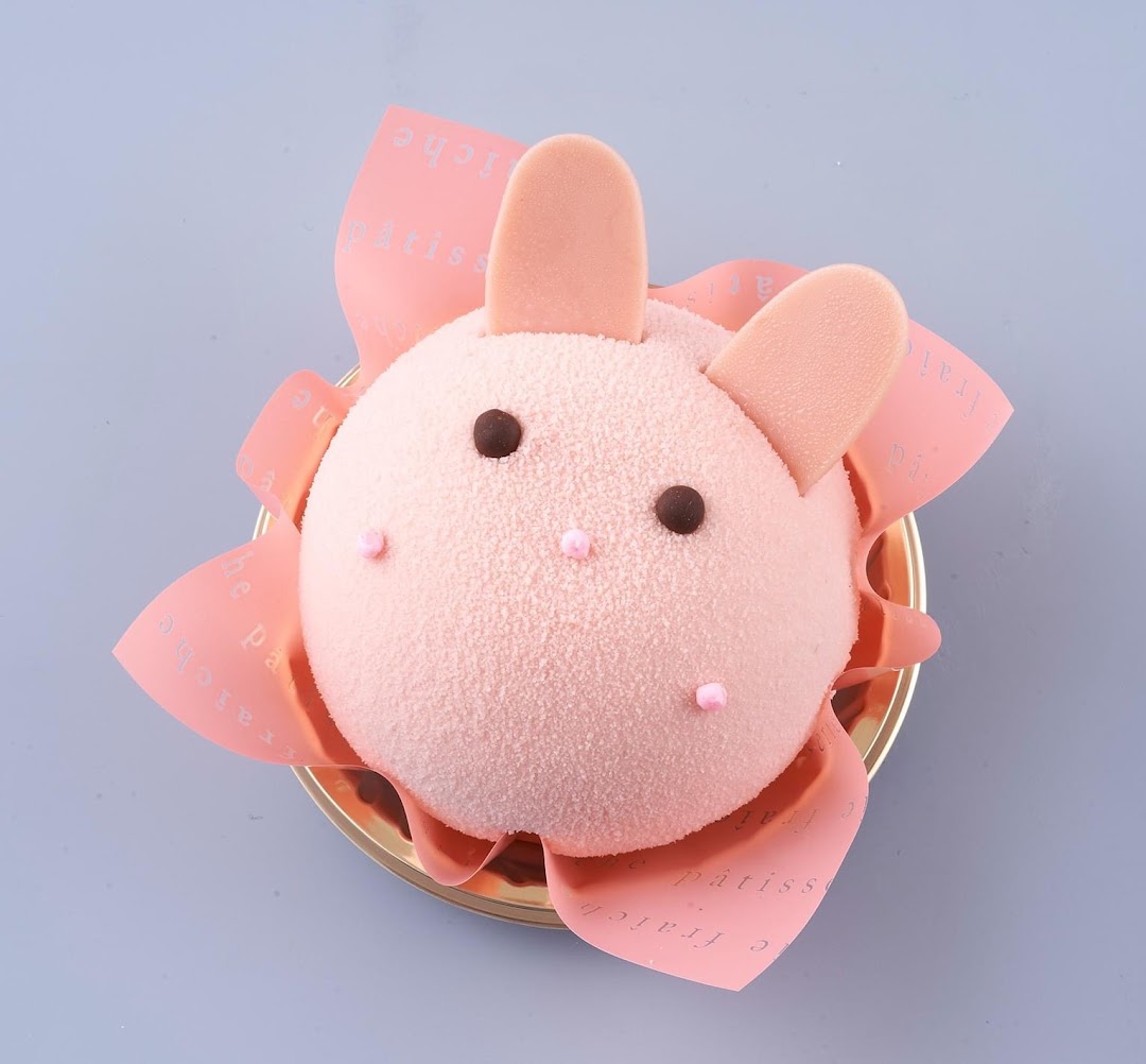 A pink, bunny-shaped dessert with chocolate eyes and pink ears.