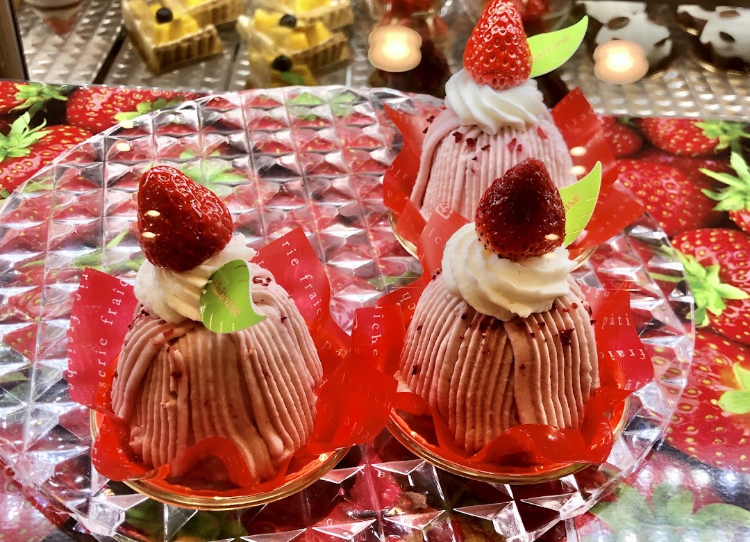 Three strawberry-topped pastries displayed on a clear tray.
