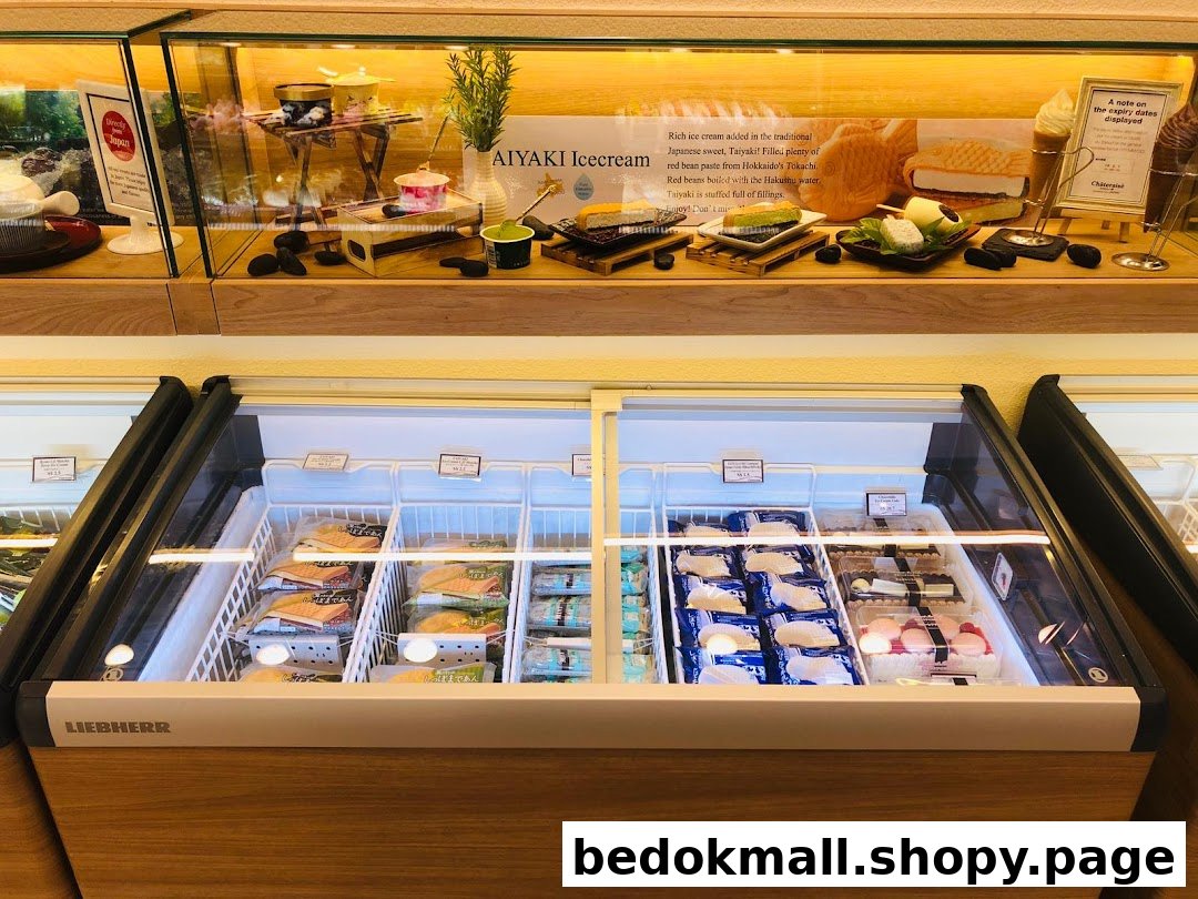 Shop interior with a display case of dessert models and freezers of packaged goods.