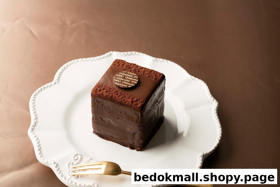 A chocolate cake on a white plate with a golden fork.
