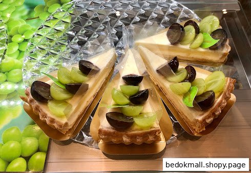 Several slices of grape tart are displayed on a clear stand.