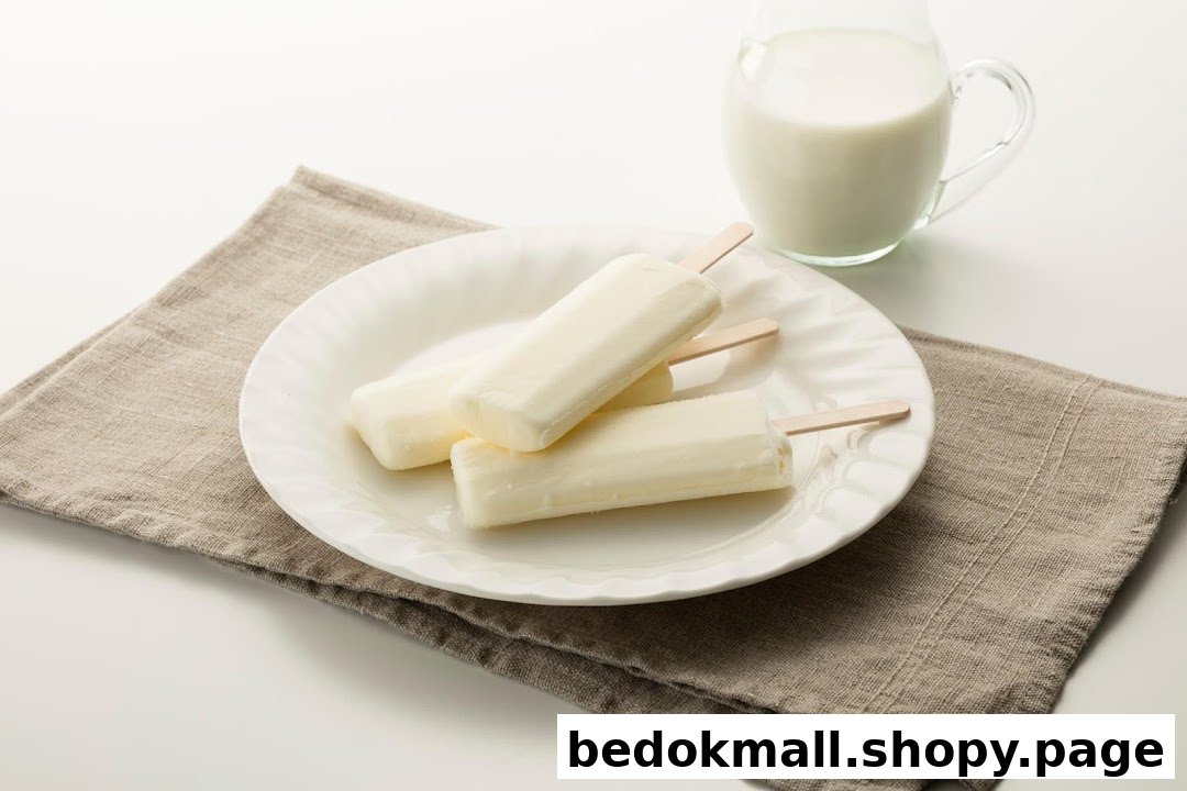 Three white popsicles on a plate with a pitcher of milk and napkin.