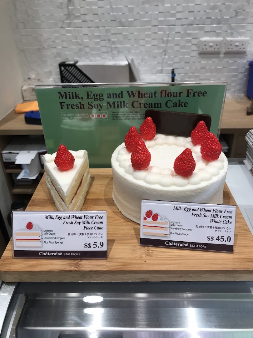Cakes and their price tags displayed on a wooden board.