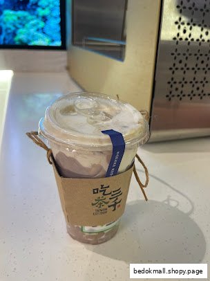 A plastic cup with a drink and a brown sleeve on a counter.