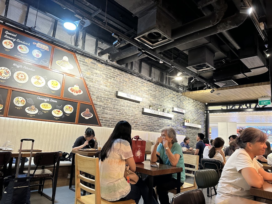Customers enjoy treats at COFFEESARANG, featuring a prominent menu board with waffles, sandwiches, and croffles.