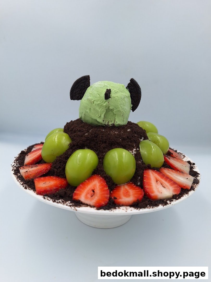 A dessert with green ice cream, cookie crumbs, grapes, and strawberries.