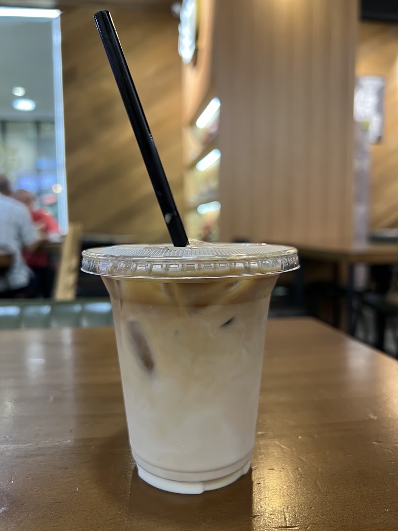 Iced coffee in a plastic cup with a straw on a wooden table.