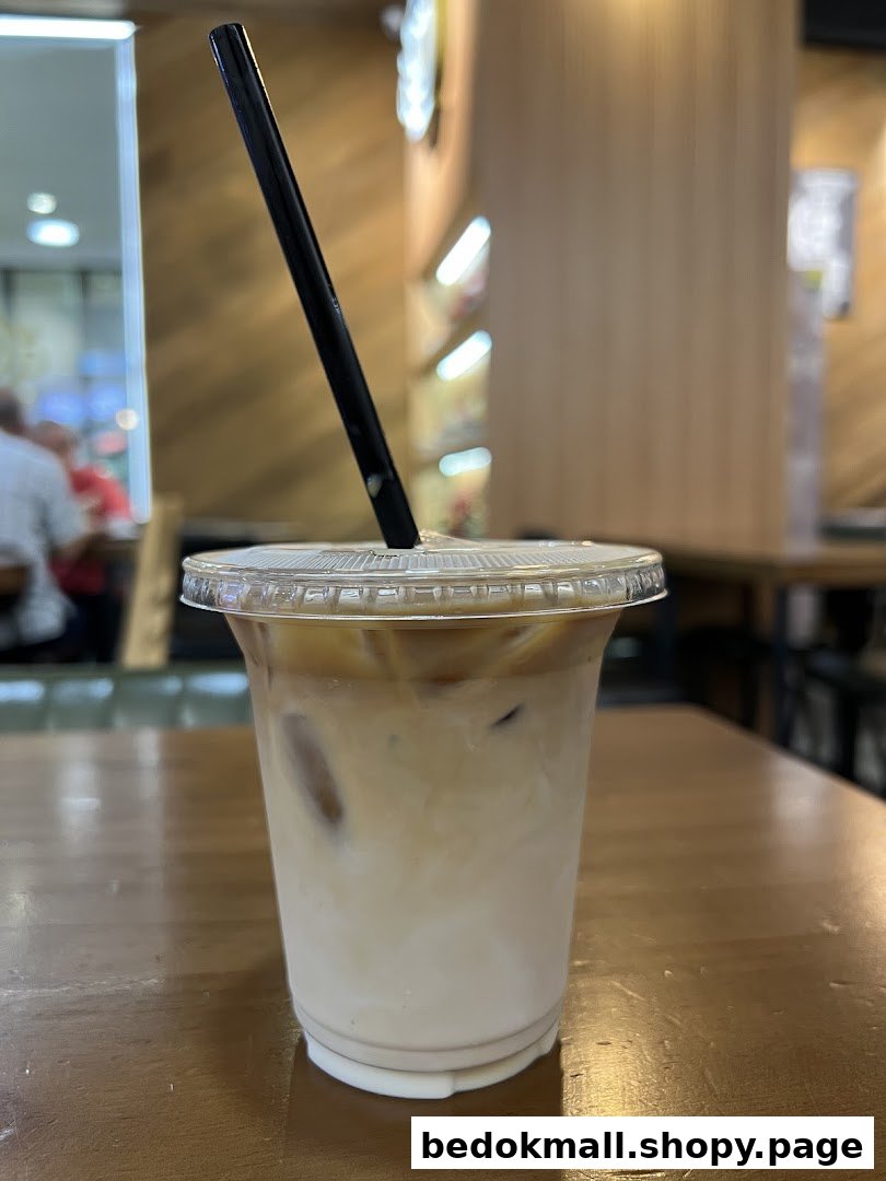 Iced coffee in a plastic cup with a straw on a wooden table.