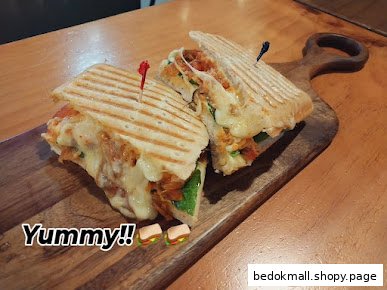 A grilled panini sandwich with melted cheese served on a wooden board.