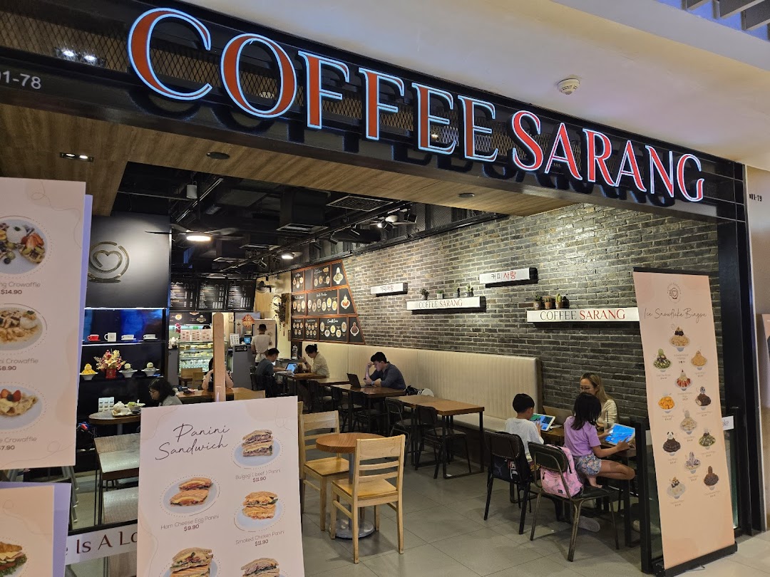 Coffee shop entrance with prominent signage and customers inside.