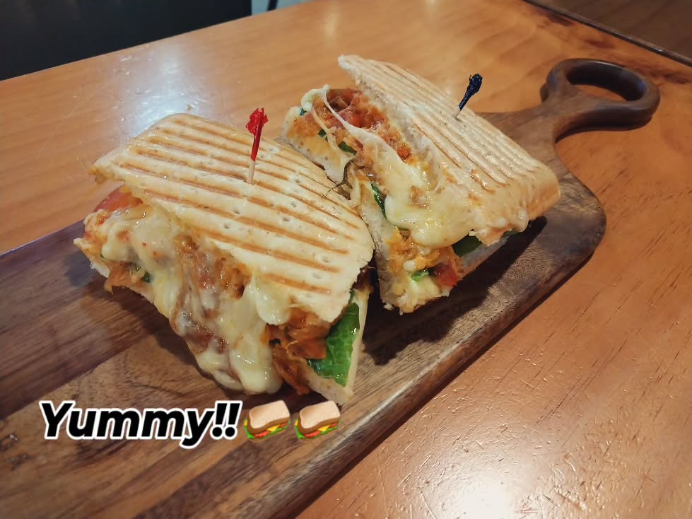A grilled sandwich with melted cheese served on a wooden board.