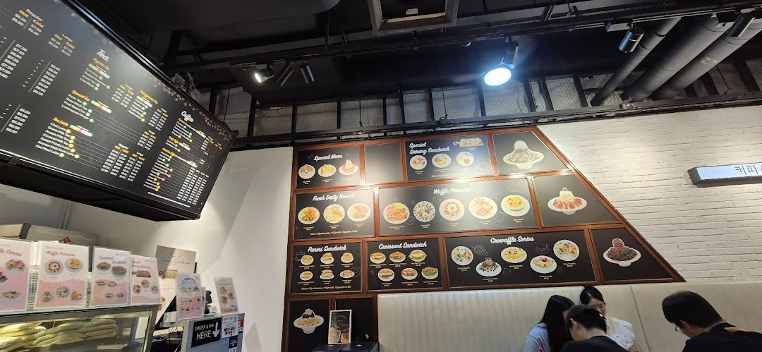 Interior view of a coffee shop with large menu boards and customers.