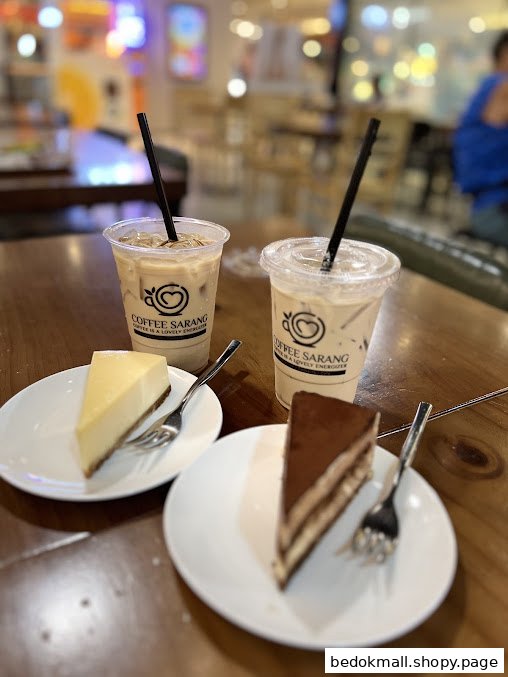 Two iced coffees and two cake slices on a table in a cafe.