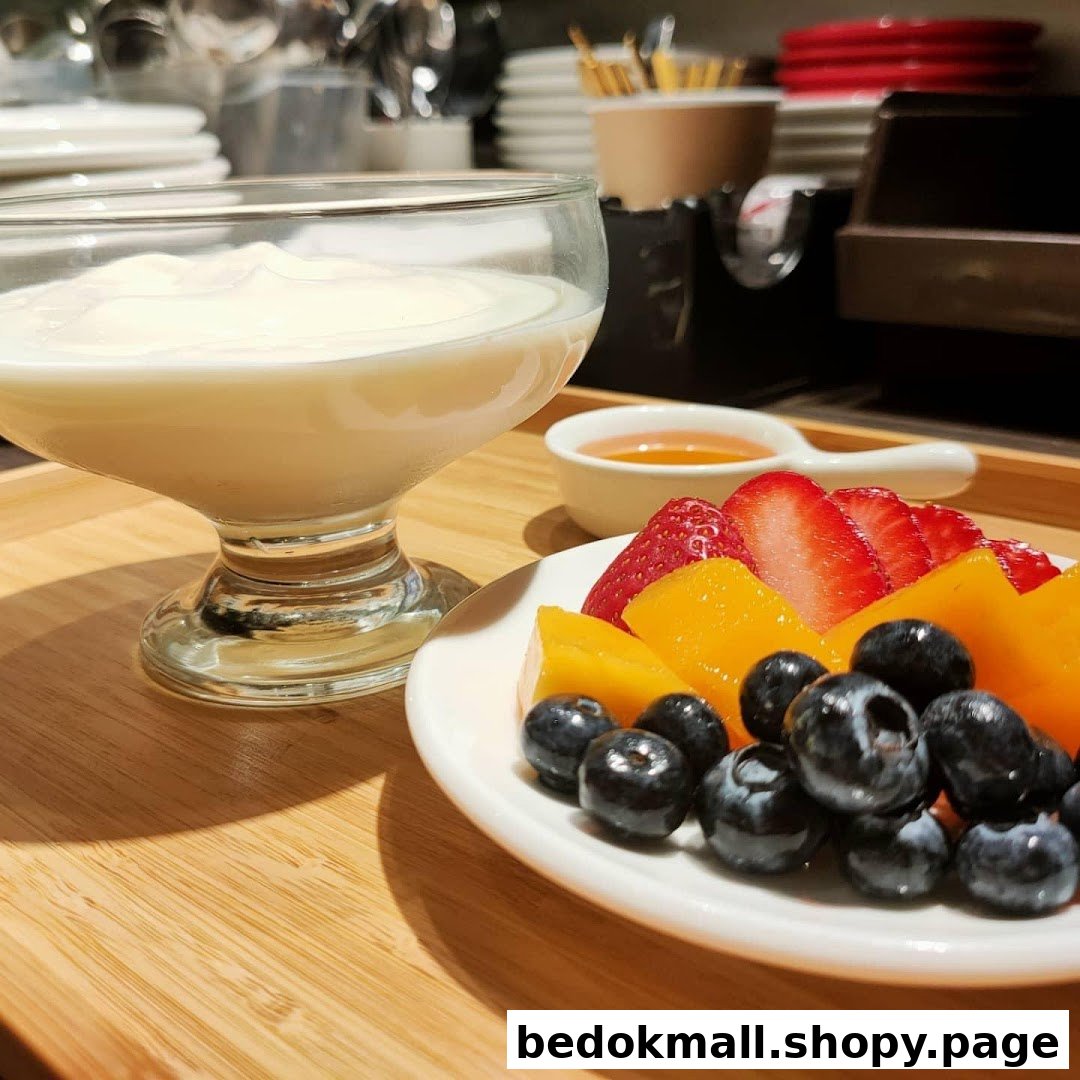 Yogurt with mixed berries, mango, and honey on a wooden tray.