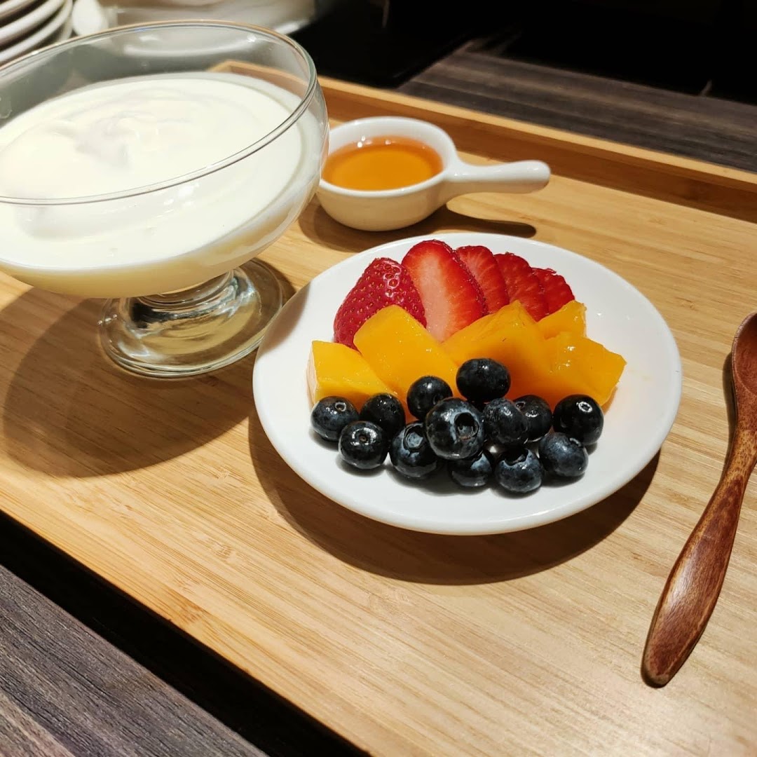 Yogurt, mixed fruit, and honey served on a wooden tray.