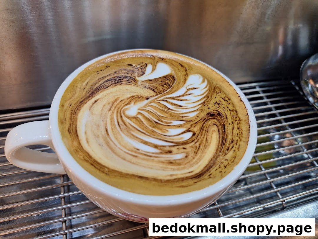 Close-up of a coffee cup with intricate latte art on a metal grate.