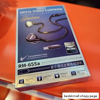 A product box for metal wired earphones is displayed on an orange surface.