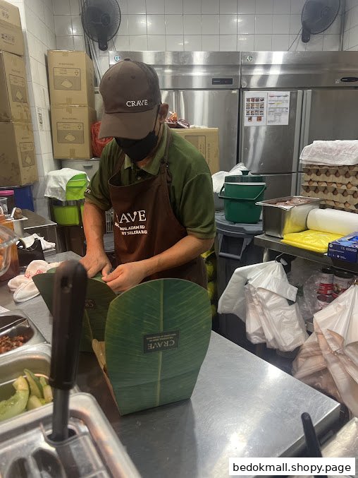 A staff member in a cap and apron is preparing food in a commercial kitchen.