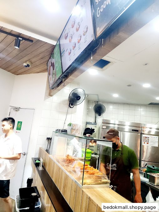 Interior view of a food stall with a counter, staff, and digital menu boards.