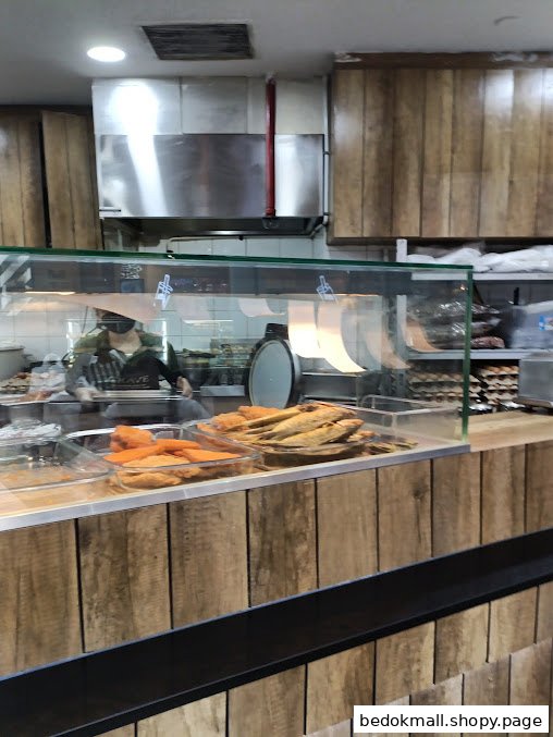 Interior view of a food counter with staff and displayed food items.