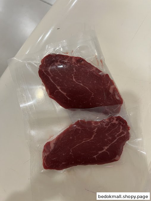 Two vacuum-sealed raw meat cuts on a white surface.