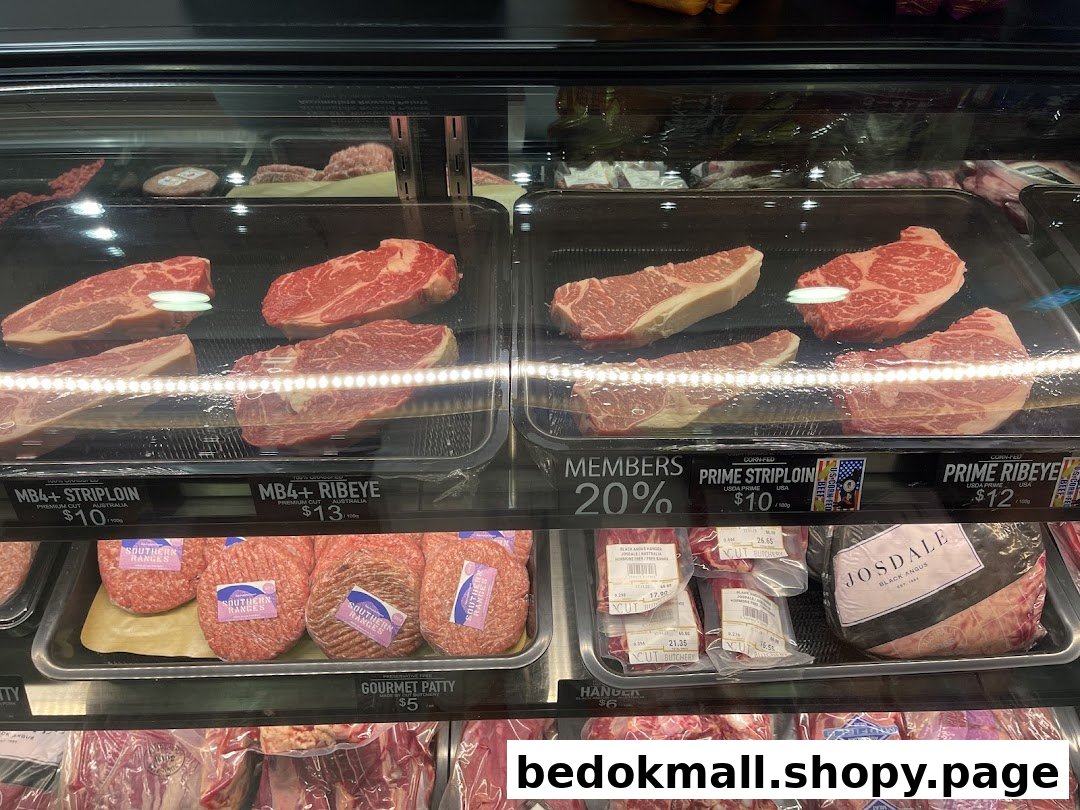 A refrigerated display case filled with various cuts of fresh meat and price labels.
