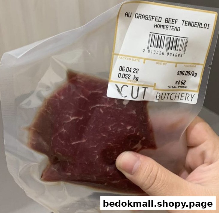 A hand holds a vacuum-sealed beef tenderloin package with a price label.