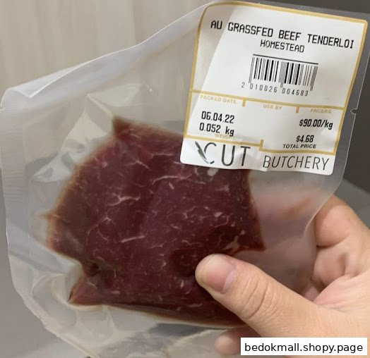 Hand holding a vacuum-sealed package of beef tenderloin with a price label.