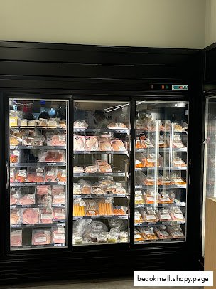 A large refrigerated display case filled with packaged meat products inside a butchery.