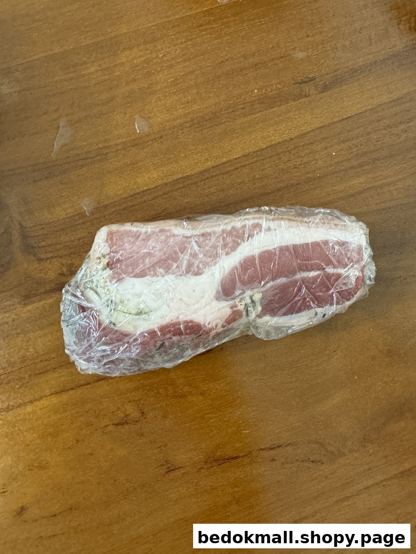 A piece of raw meat wrapped in plastic on a wooden surface.