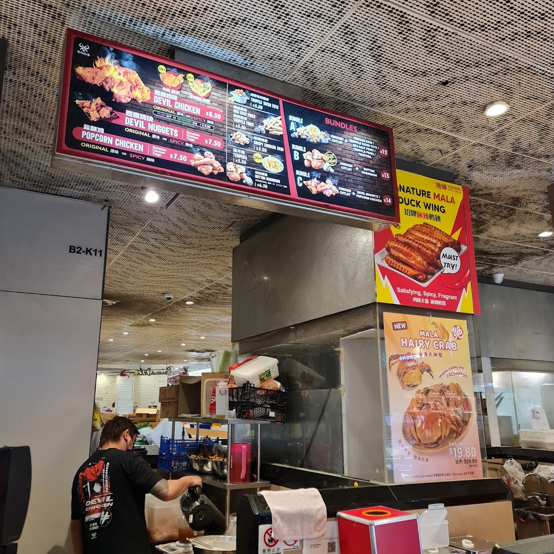 Large digital menu board displaying chicken dishes and bundles at a food stall.