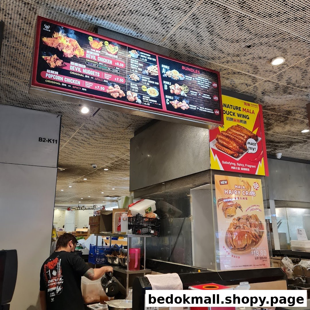 Large digital menu board displaying chicken dishes and bundles at a food stall.