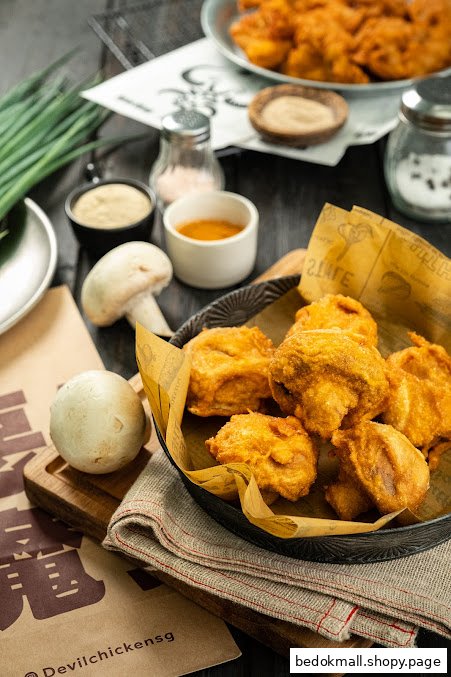 A basket of fried chicken pieces with mushrooms, sauces, and branding.