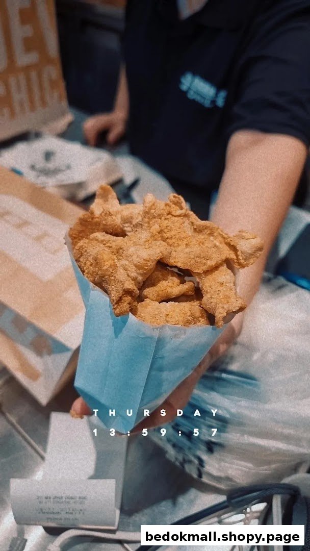A person holds a blue bag filled with fried chicken pieces.