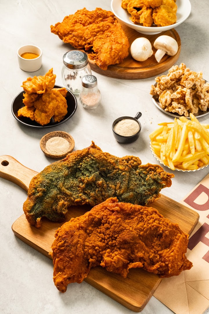 Assortment of fried chicken cutlets, fries, and other snacks on a table.
