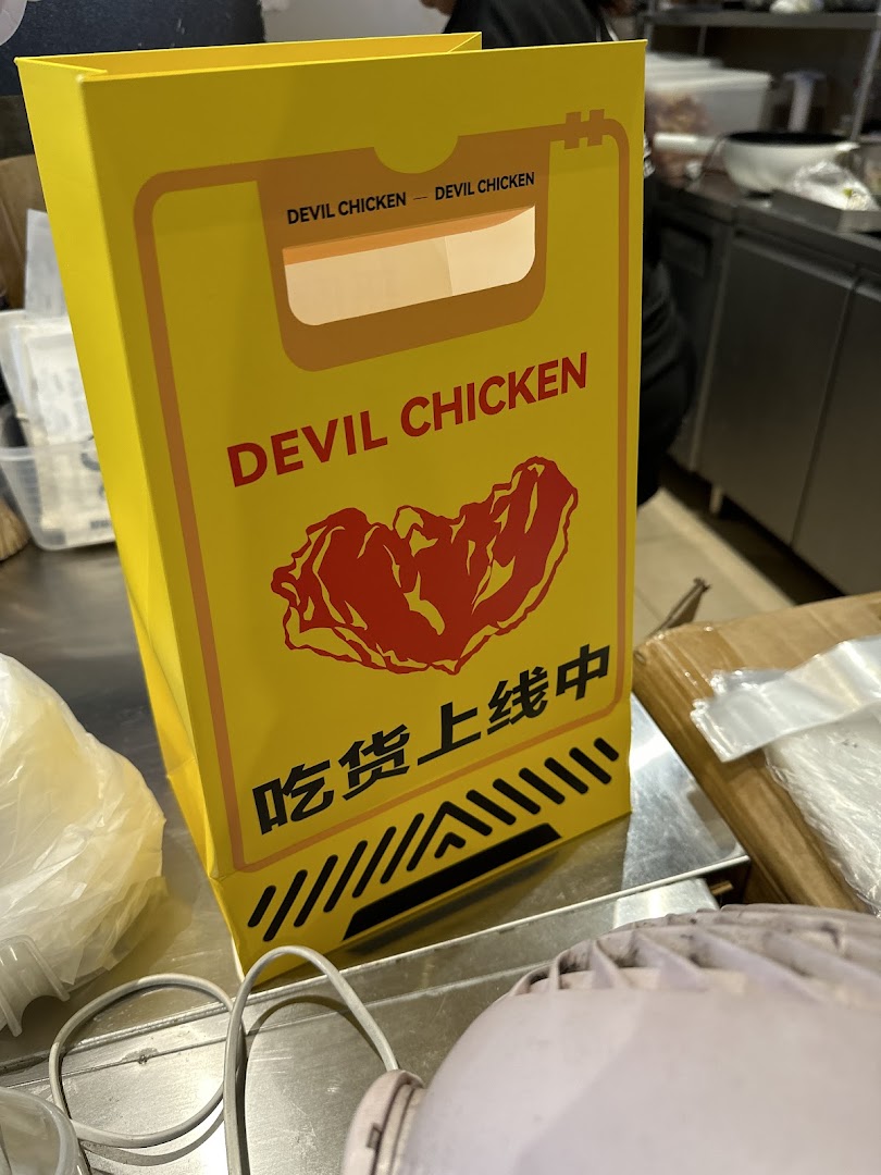 A yellow Devil Chicken branded bag sits on a metal counter.