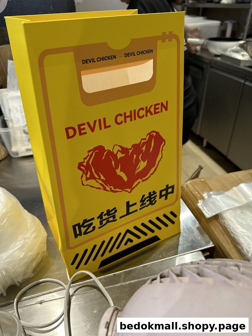 A yellow Devil Chicken branded bag sits on a metal counter.
