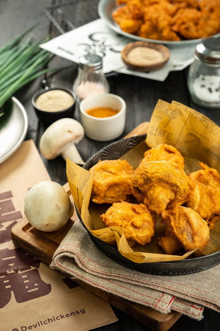 Close-up of fried chicken/mushrooms with ingredients and sauces on a table.