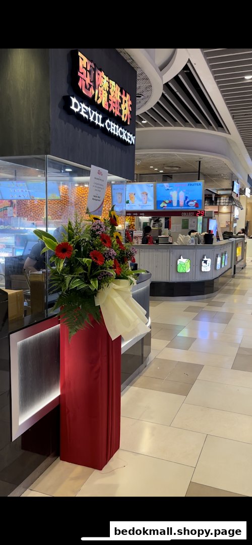 Interior view of a mall with a "Devil Chicken" shop and a flower arrangement.