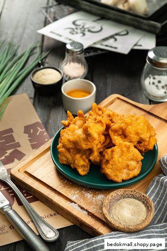 A plate of fried chicken with condiments and utensils on a wooden table.